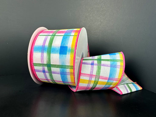 A spool of 4X10Y Multi Watercolor Tuttola Plaid Ribbon 41545-04-01 with pink edges is partially unrolled against a dark background, showcasing its wired design with blue, green, yellow, and pink stripes.
