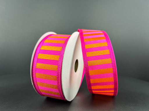 Two spools of the 1.5X10Y Fuchsia Satin-Orange Stripes/Orange Edge Ribbon are displayed upright, elegantly wrapped around white cylindrical cardboard holders against a dark backdrop.