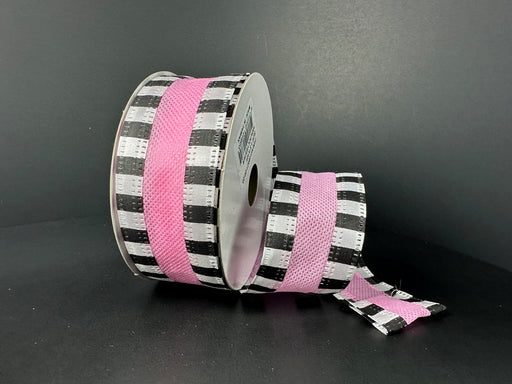 Displayed against a dark background, two spools of 1.5X10Y Pink Flat Breeze/Black And White Stripe Edge Ribbon (46521-09-03) showcase a black and white checkered pattern with a central pink stripe. One spool stands upright while the other lies down with ribbon partly unwound.