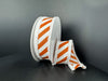 Two white circular boxes are decorated with 1.5x10Y orange flat all glitter/white diagonal stripe/white fuzz stripe ribbon (51503-09-01). One box is upright; the other lies on its side with ribbon cascading onto the surface.