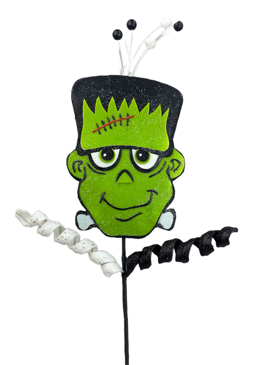 Introducing the 26" Green Frankie Pick 56961GN: a festive Halloween decoration showcasing a cartoonish, smiling green monster face complete with big eyes, a stitched forehead, and side bolts. The design is accentuated by its black felt top adorned with curled white and black ribbons extending from the back, adding an element of spooky charm.