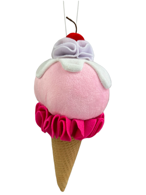 The 11 by 4 Pink Ice Cream Ornament (63418PK) is a plush toy on a string, designed like an ice cream cone. It features a pink scoop with white and lavender whipped cream, topped with a red cherry, all sitting above a tan cone adorned with hot pink ruffled trim.