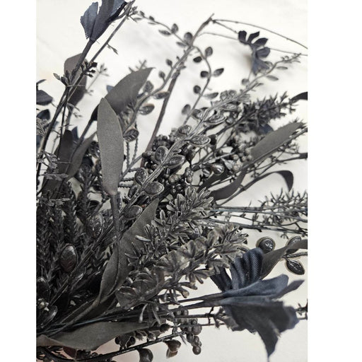 A close-up of the 24 Black Mixed Halloween Spray 63526-BK, featuring artificial black flowers and leaves against a white background, highlighting the detailed textures of the petals, stems, and foliage.