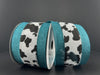 Two spools of 2.5X10Y Bw Cow Print Linen/Teal Edge Ribbon are side by side against a dark gray background. These wired ribbons add a whimsical touch to any project.