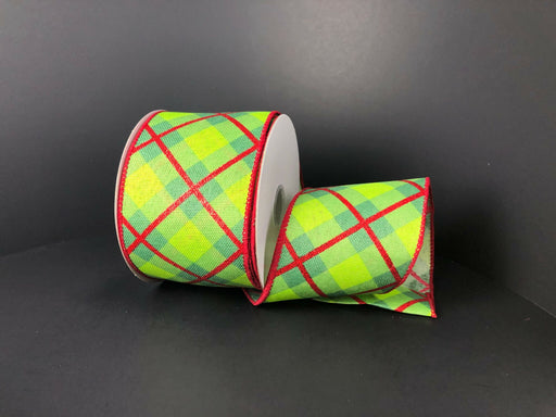 Two rolls of the 2.5X10Y Green-Red Georgina Plaid ribbon, featuring green, blue, and yellow patterns with red edging on a black background, are displayed with one roll upright and the other leaning elegantly.