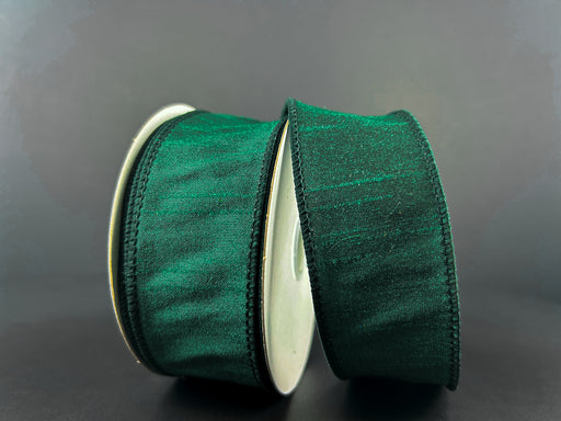 Two rolls of the 1.5"x10Y Hunter Green Faux Dupioni Ribbon stand out against a neutral gray background. The satin-finish ribbons are neatly wound on white spools, highlighting their thin black edges, and bring an elegant touch with their wired structure for easy shaping.