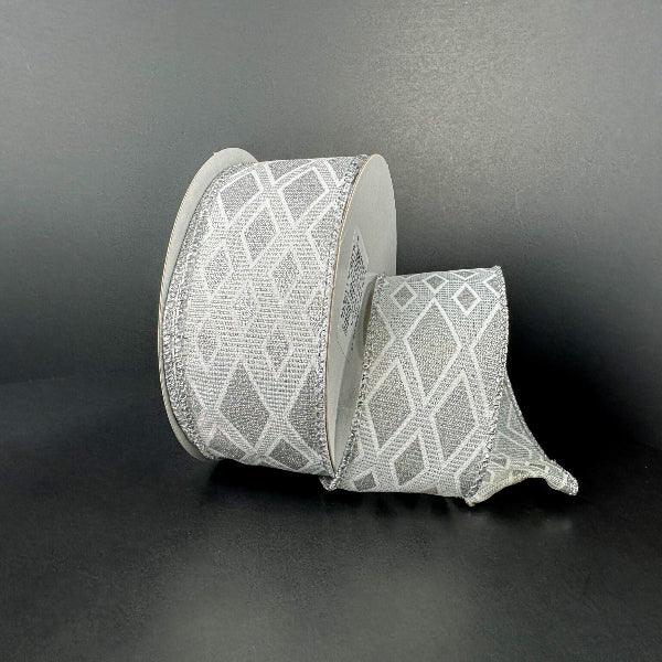 A spool of 1.5X10Y White-Silver Linen/Silver Metallic Diamond Cascade Ribbon (73559-09-16) with a geometric silver diamond pattern is unwound on a dark, plain surface and background.