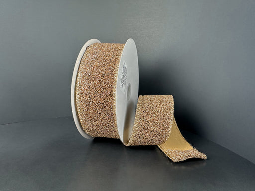 A large roll of 1.5X10Y Toffee-Black Fuzzy Metallic Ribbon (73566-09-35) is displayed on a white spool, with part of the strip unrolled and laying flat against a dark surface—resembling an industrial toffee ribbon.