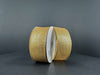 Two rolls of 1.5X10Y Gold Stairstep Woven Metallic Ribbon (76310-09-15) with white centers stand upright on a dark gray background, their glittery metallic stairstep design reflecting the light.