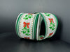 Two rolls of 2.5x10Y Ivory Linen/Mistletoe Bow/Green Edge Ribbon (76502-40-07) are displayed on a dark gray surface with a gray background.