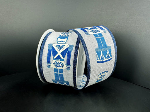 Two rolls of 2.5X10Y Chinoiserie Nutcracker Ribbon 76529-40-05 feature blue nutcracker soldiers on a plain dark background, adding a classic touch to your décor.
