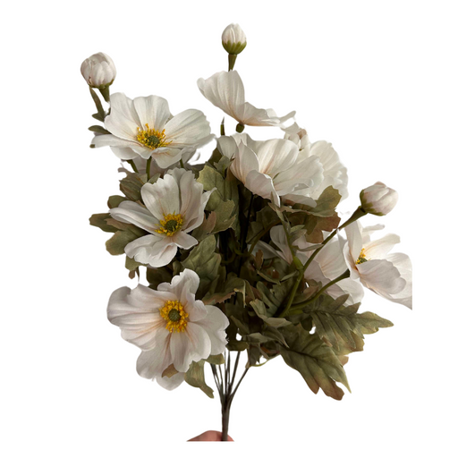A hand holds an ivory bouquet of the 21 In Cosmos Bush X 11 84566-Ivory. The arrangement features white poppies with yellow centers and light green leaves in various bloom stages against a white background.