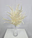The 21 Cream Fern Bush (85360-UV-CR) with delicate, fern-like cream leaves is displayed in a clear glass vase on a light surface, set against a plain light gray wall.