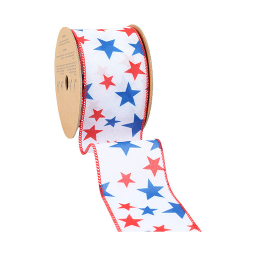 The 2.5 White with Red and Blue Stars Wired Ribbon features a star pattern on a white background with red edge stitching and is partially unraveled from a brown cardboard spool.
