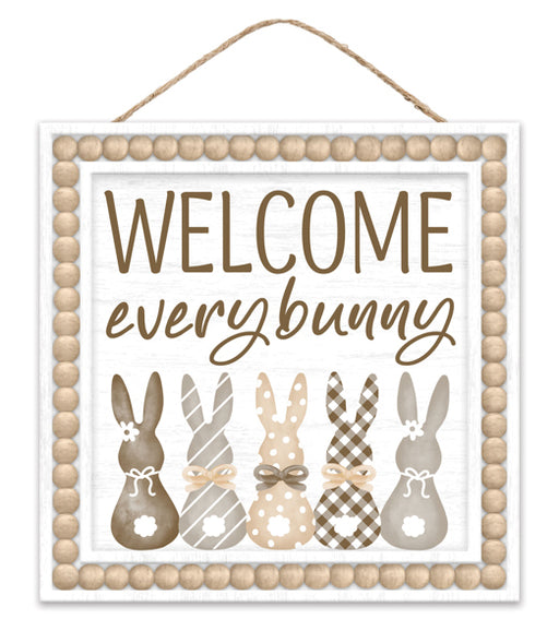 The 10SQ Welcome Every Bunny Sign (AP737882) features five patterned bunny silhouettes in neutral tones, each adorned with a bow. Playful script greets you, and a wooden bead border completes this charming MDF decor piece for your home.