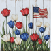 The 10 x 10 American Flag & Tulips Sign TTE-188 displays red, white, and blue tulips on a wooden background with an American flag in the top right corner, evoking a patriotic theme that embodies national pride.