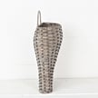 The 11 by 13.5 by 4 Curvy Basket (M21202IEI) features a tall, narrow shape with a rounded base, textured weave, and single curved handle. Its shown against a white wall on a light surface.