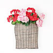 The 11 by 13.5 by 4 Curvy Basket M21202IEI is shown filled with red and pink artificial flowers, set against a plain white background.