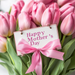 The 10 x 10 Mothers Day Tulip Bouquet Sign TTE-225, elegantly inscribed with Happy Mothers Day and decorated with a pink ribbon bow, is perfect for celebrating the special day.