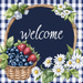 The 10 x 10 Navy Gingham Welcome Summer Sign TTE-262 features a circular script welcome on a navy gingham background, surrounded by daisies and flowers with a basket of blueberries and strawberries, making it a charming addition to any home.