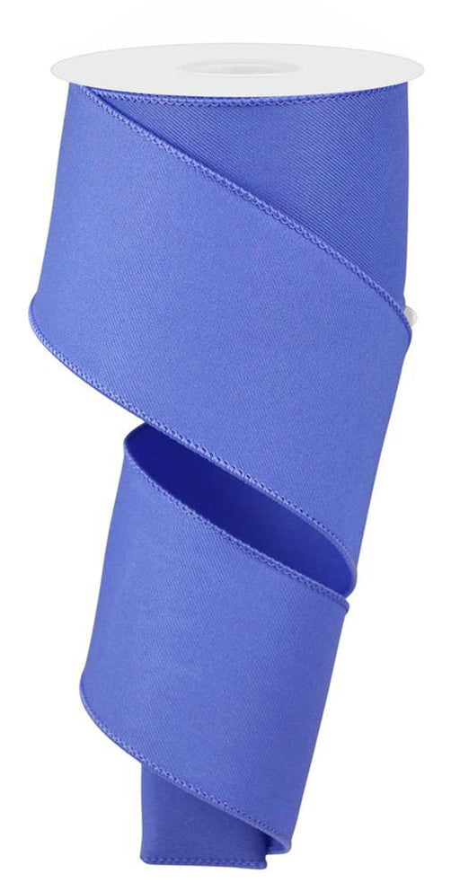 The 2.5X10Yd Iris Blue RGE1203Y4 ribbon unwinds in a spiral, showing off its slightly shiny diagonal weave, while attached to a white circular spool at the top, forming a smooth descending curve.