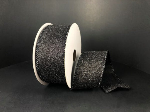 A spool of 1.5X10Y Black All Flat Glitter Ribbon (X820609-21) is shown against a black background, with part of the sparkling ribbon unrolled and draped in front.