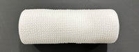 A close-up of the 10X10Y White All Snow Fuzz Mesh XB253610-01 medical bandage roll, showcasing its textured surface against a black background.