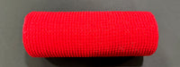 A 10X10Y Red All Snow Fuzz Mesh (XB253610-12) roll rests horizontally on a dark flat surface, displaying its vibrant color and tightly woven, neatly cylindrical form.