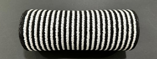 A cylindrical object wrapped in 10X10Y Black-White All Snow Fuzz Stripe Mesh XB253810-20, featuring alternating black and white vertical stripes, is placed on a dark, flat surface.