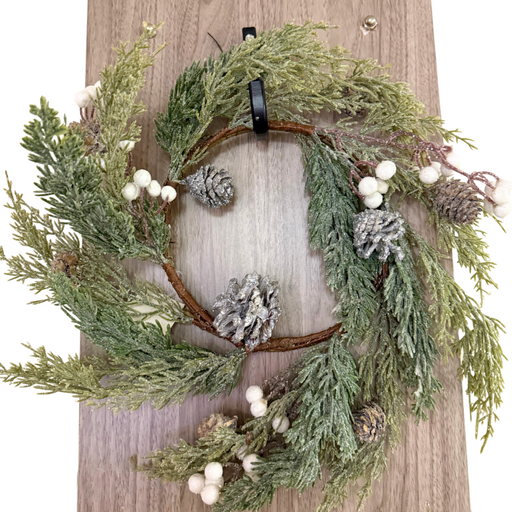 A 6.5 White Sparkle Soft Pine White Berry Ring (ISB78002) featuring pine branches, white berries, and a hint of sparkle hangs on a wooden door.