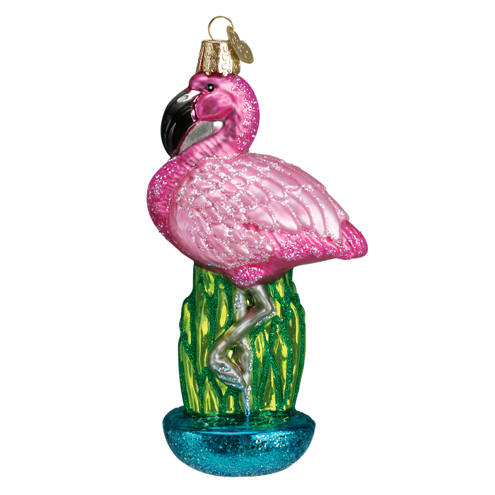 The Flamingo Ornament Old World Christmas 16023 showcases a glittery pink flamingo, gracefully balanced on one leg on a lush green cactus, complete with a gold hanging hook.
