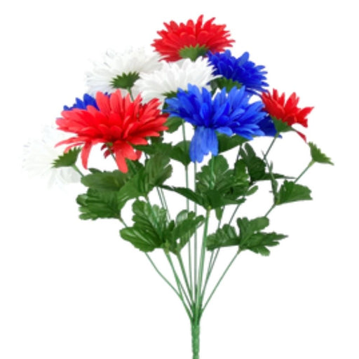 The 18 Gerber Daisy Bush (30550RWB) features 12 stems of vibrant red, white, and blue blooms with lush green leaves and stems, creating a stunning display against a plain white background.