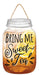 The 10H X 6L Bring Me Sweet Tea Sign (AP7190) in White/Rust/Yellow showcases a mason jar illustration filled with iced tea and lemon slices, featuring a string handle. Made from MDF, it serves as charming wall decor with the bold text Bring Me Sweet Tea in decorative lettering.