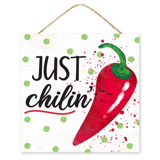 The 10 Just Chilin Chili Sign AP7103 features a smiling red chili pepper on the right, with Just Chilin in bold black letters on the left, set against a green-dotted white background. Its made of MDF paper and includes a rope for easy hanging.