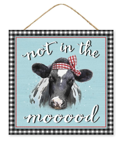 This 10 square MDF sign, Not In The Mood, SKU AP7138, features a cow with a red checkered bow on a light blue background. A playful white script reads not in the mooood, and a black and white checkered border adds to its quirky decor charm.