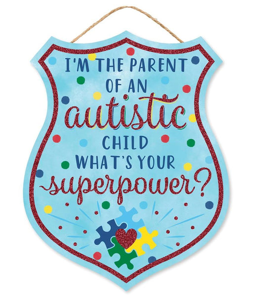 The 12H x 9.5L Parent/Autistic Child Badge (AP8919) features a shield-shaped MDF design with colorful polka dots, reading Im the parent of an autistic child. Whats your superpower? and decorated with a heart and jigsaw puzzle pieces on the bottom in turquoise, red, yellow, and blue.