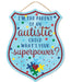 The 12H x 9.5L Parent/Autistic Child Badge (AP8919) features a shield-shaped MDF design with colorful polka dots, reading Im the parent of an autistic child. Whats your superpower? and decorated with a heart and jigsaw puzzle pieces on the bottom in turquoise, red, yellow, and blue.