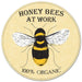 The 12Dia Metal Honey Bee Sign (MD0459) in yellow/black/white features a central bee illustration, honeycomb background, and the words “HONEY BEES AT WORK” above and “100% ORGANIC” below—ideal for highlighting active honey bees.