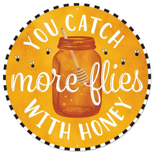 The 12Dia Catch More Flies Metal Sign (MD0781) has a honey jar with bees illustration and the saying, You Catch More Flies with Honey, on an orange background featuring a black and white border. Its both stylish and whimsical for home decor.