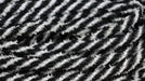 The 8Mm X 20Yd Snowdrift Deco Flex Tubing Black/White RE3225K2 features black and white diagonal stripes in a textured, woven design reminiscent of snowdrifts, creating a dynamic visual appeal.