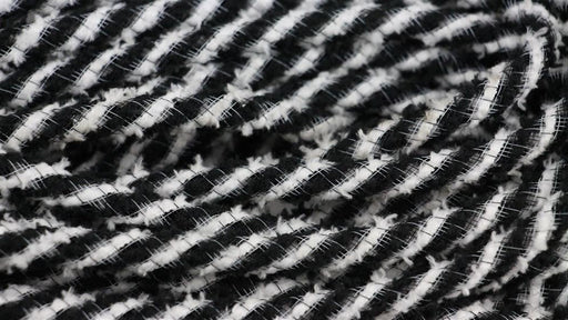 The 8Mm X 20Yd Snowdrift Deco Flex Tubing Black/White RE3225K2 features black and white diagonal stripes in a textured, woven design reminiscent of snowdrifts, creating a dynamic visual appeal.