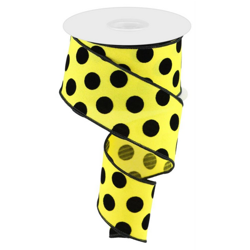 The 2.5 X 10Yd Velvet Polka Dots RGC162929 ribbon is displayed with a vibrant yellow background and large black polka dots, elegantly featuring its bold pattern and wire edge partly unwound.