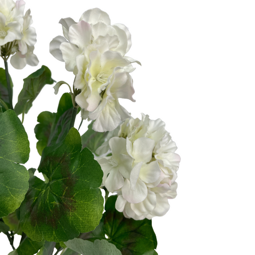 The Cream Geranium Bush SB781388-045 features artificial white flowers with ruffled petals, hints of pink, and vibrant green leaves elegantly mimicking a geranium bush against a light cream backdrop.