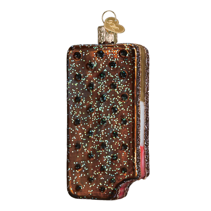 The Ice Cream Sandwich 32287 Old World Christmas Ornament is adorned with chocolate chips and features a bite revealing white and pink layers. A metal cap and loop on top ensure this festive decoration hangs perfectly on your tree.