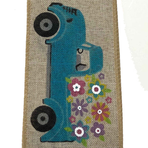 The 2.5 Tan Linen Blue Truck Flowers Ribbon (Q921740-14) features a blue vintage sewing machine with black wheels, colorful flowers at the base, stitched edges, a synthetic wire edge, and comes in a 10-yard length.