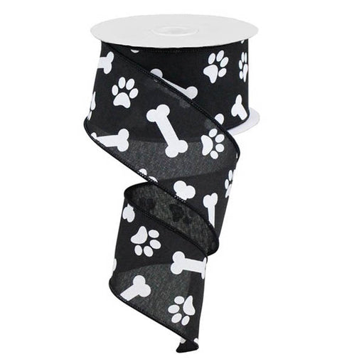 A spool of 2.5 Black with White Paw Prints & Bones Ribbon RGA115102, featuring white paw prints and dog bones, is partially unrolled in a spiral shape.