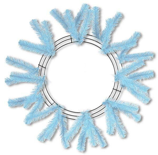 The 24 Work Wreath Sky Blue XX748869 features light blue artificial pine branches on a metal frame, arranged in a circular snowflake pattern. The open center reveals the white background, highlighting its elegant simplicity.